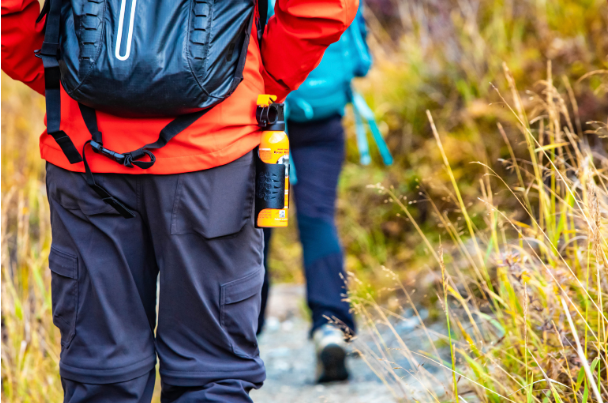 A person hiking with a can of bear spray attached to their hip