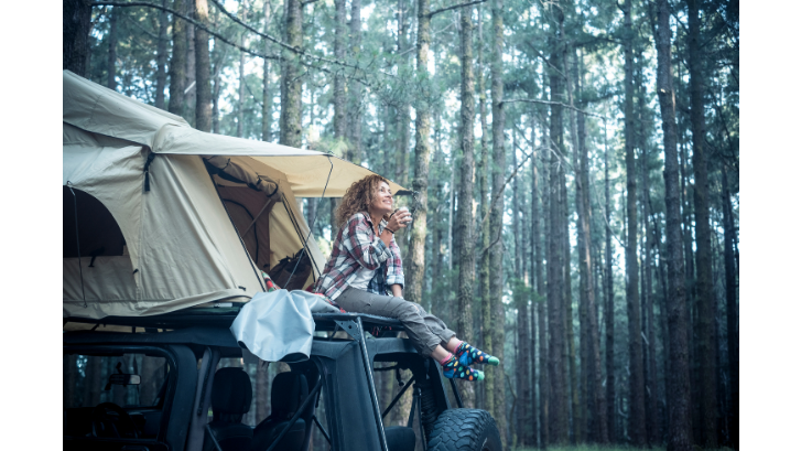 Woman drinking hot coffee in her rooftop tent