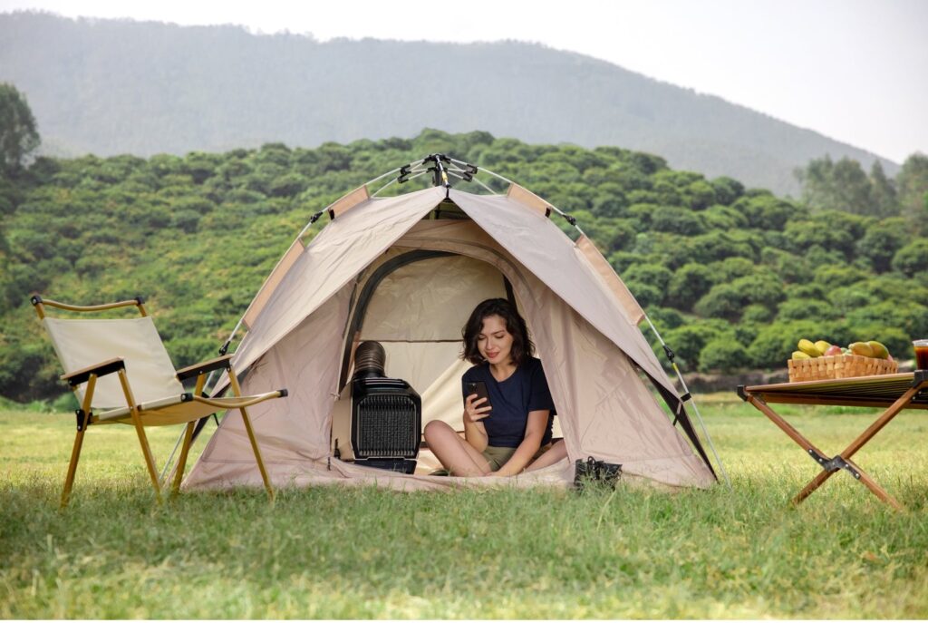 Person sitting in tent with camping air conditioner.