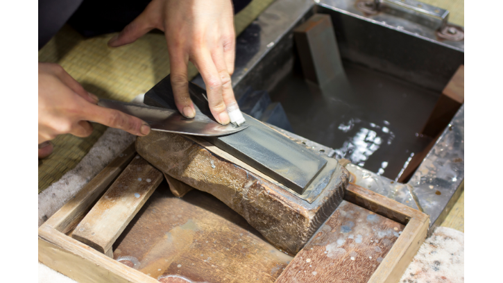 person sharpening knife on sharpening stone