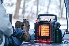 A person sitting next to a portable heater on a cold day