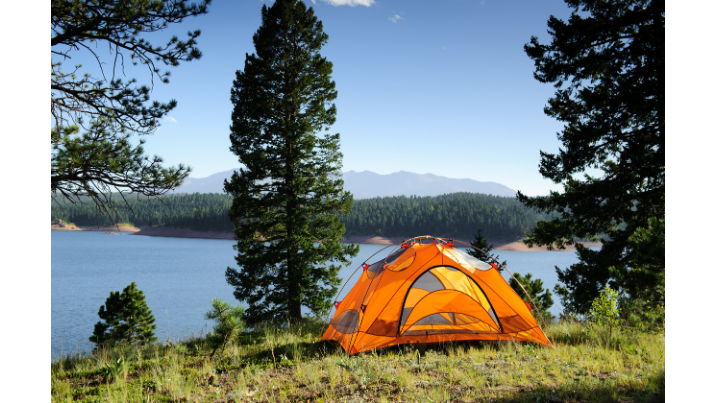 A pop up tent set up up by a lake in the forest.