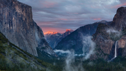 a valley between two mountains on a cloudy day at sunset