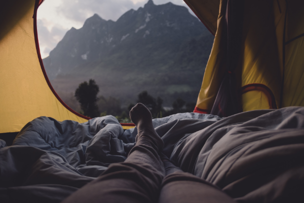 a person laying in a tent looking at a view of a mountain