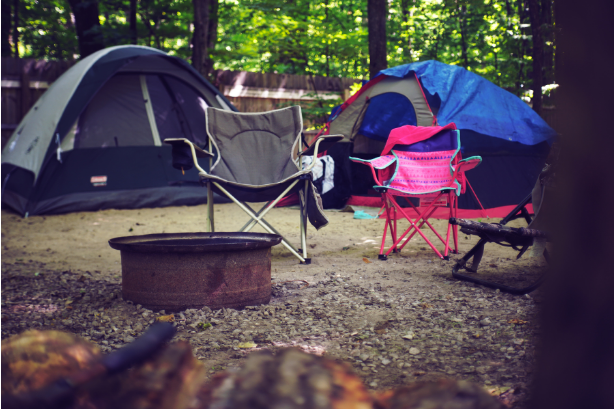 An adult and kids camping chair at a campsite