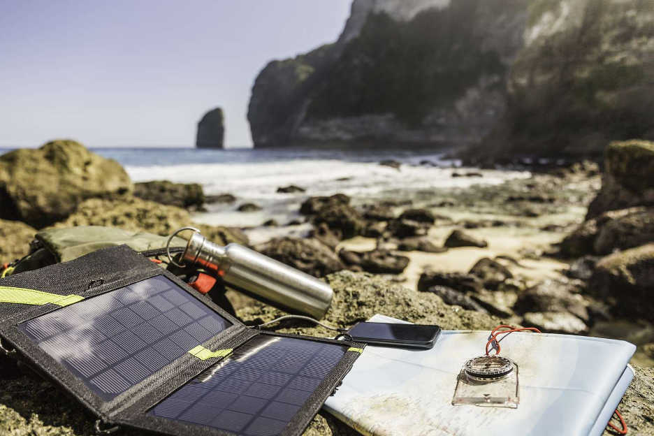 A solar panel and a compass on a rocky beach