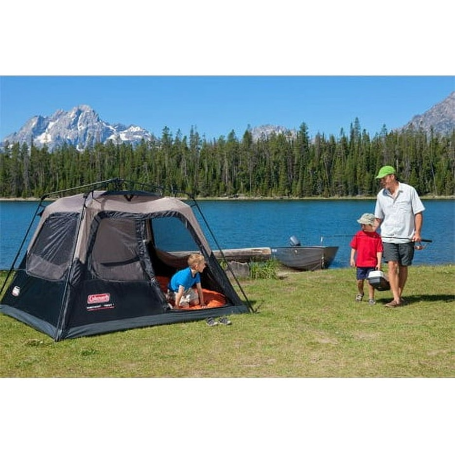 A Father and sons standing next to pop up tent near lake