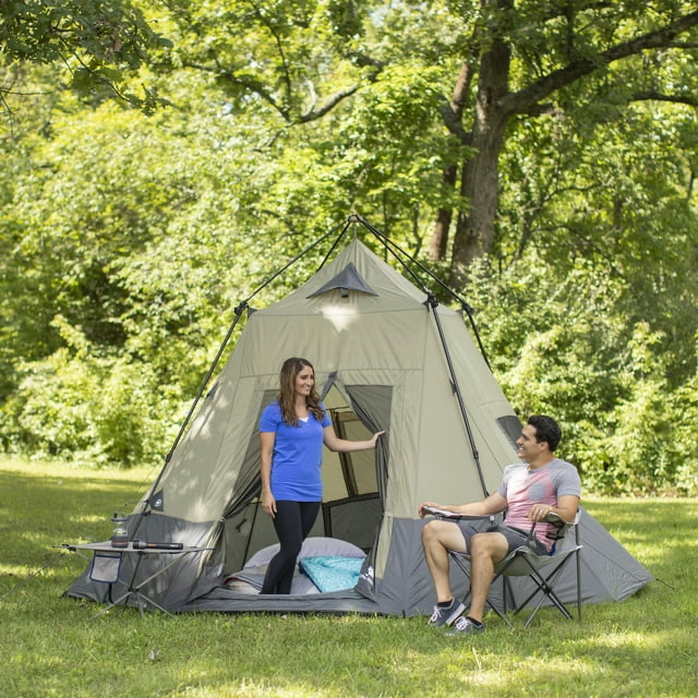 A couple sitting in a pop up tent next to the forest