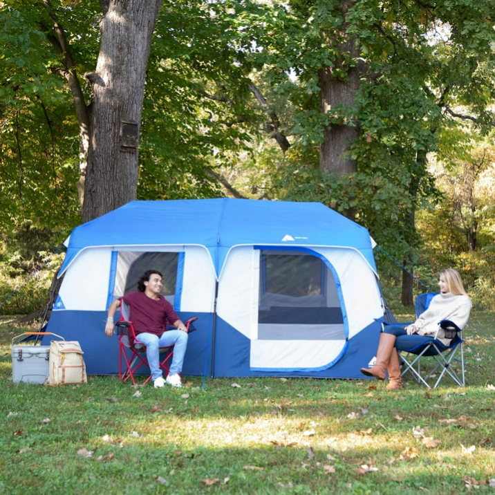 Two people sitting next to a pop up tent