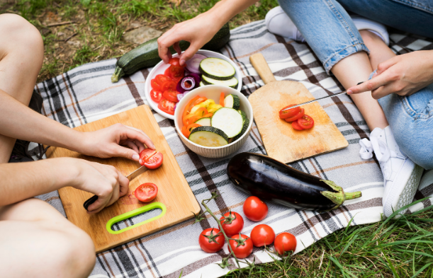 Two people cutting up vegetables