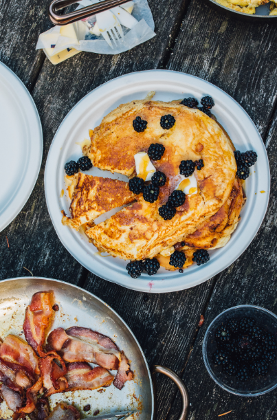 Blackberry pancakes and bacon on a table