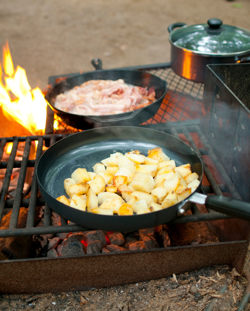 Potatos and meat cooking over campfire