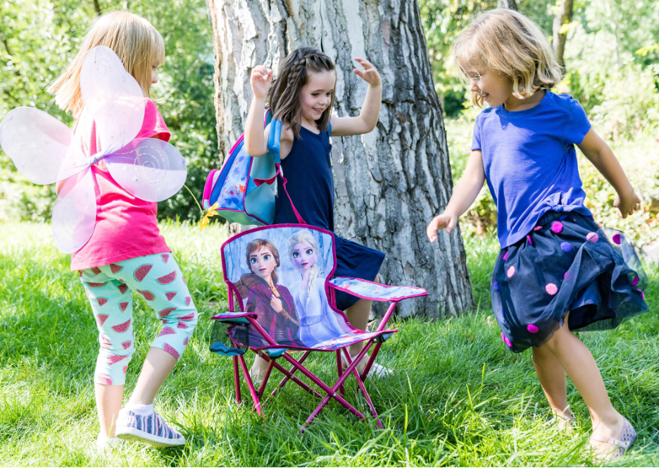 three girls playing around a camping chair