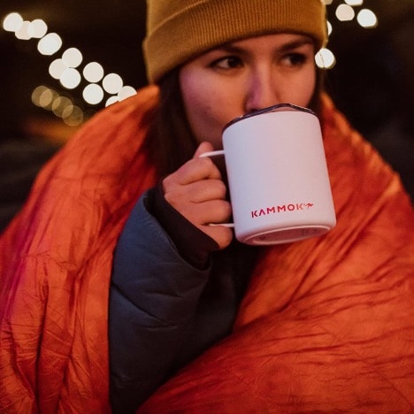 A person in a blanket drinking from a mug